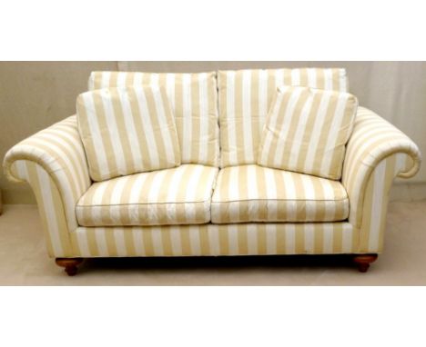 A modern two seater sofa with loose cushion upholstered in a cream and primrose striped cotton fabric, raised on turned legs,