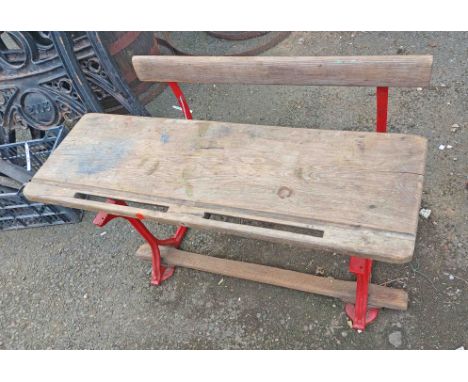 A Vintage school desk of bench form, with wooden top and bench, set on a cast-iron base