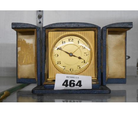 A vintage gilt metal cased travelling alarm clock with ribbed decoration, Swiss movement and original travelling case