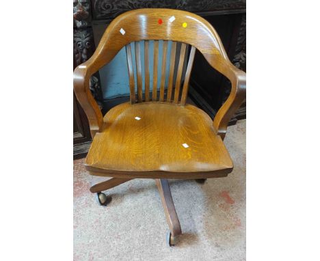 A vintage oak framed lathe back office elbow chair with moulded sectional seat, set on a swivel base with Shepherd casters