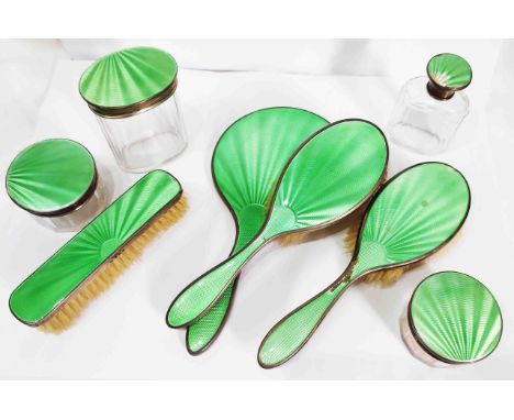 An Art Deco eight piece green enamelled silver dressing table set comprising hand mirror, three brushes, two circular pots, o