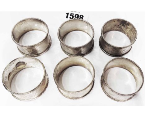 A set of six silver napkin rings with engine turned decoration and engraved initials to cartouche shields