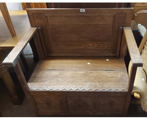 A 90cm vintage oak monk's bench with carved detail, locker seat and panelled front, set on block feet