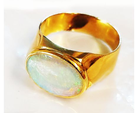 A marked 18k yellow metal ring, set with oval opal panel - size Q 1/2