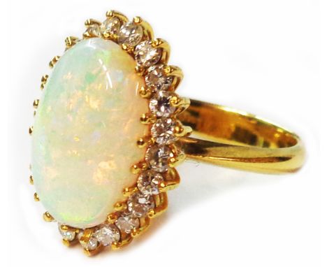 A marked 18ct/750 yellow metal ring, set with large central oval opal within a diamond border - size M 1/2 - boxed