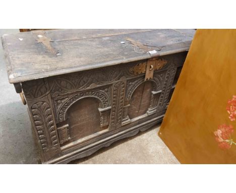 A 1.2m 18th Century oak coffer with internal candle box, heavy iron latch and strapwork hinges and carved decoration to the t
