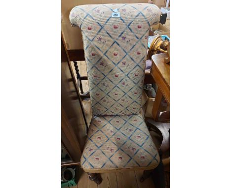 A Victorian prie dieu chair with repeat pattern tapestry upholstery, set on turned front legs with brown porcelain casters