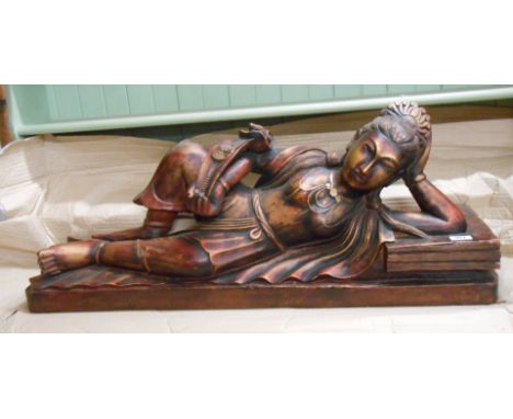 A vintage Eastern carved wood figure depicting a reclining woman