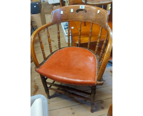 A vintage oak framed bow back elbow chair with spindles and red leather upholstered seat, set on turned supports