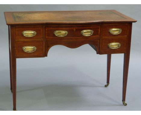 An Edwardian mahogany semi bow front writing table having an incised leather surface above a drawer to the centre and two doo