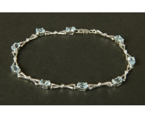 An aquamarine and diamond bracelet in 9ct white gold, the oval faceted aquamarines interspersed with bow links set to the cen