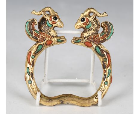 A South-east Asian Tibetan style gilt metal bangle, cast with winged beast head terminals, inset with coral and turquoise sto
