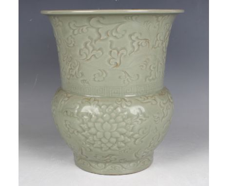 A Chinese celadon glazed stoneware jar/spittoon, the baluster body and flared neck carved in low relief with flowers and scro