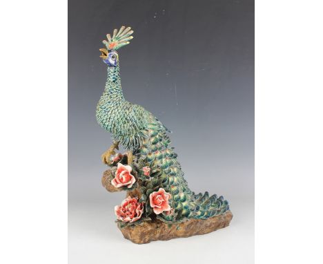 A Chinese pottery model of a peacock, 20th century, modelled on a flower encrusted rocky outcrop, the peacock with turquoise 