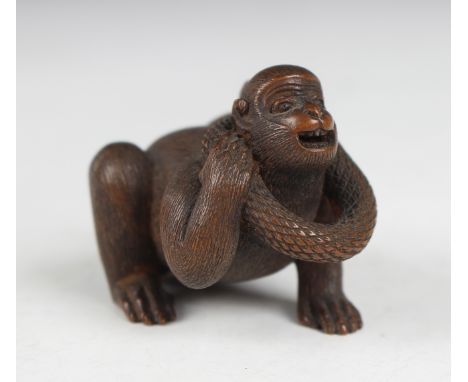 A Japanese wood okimono netsuke of a monkey and snake by Masatami, Meiji period, finely carved with a snake curled around the