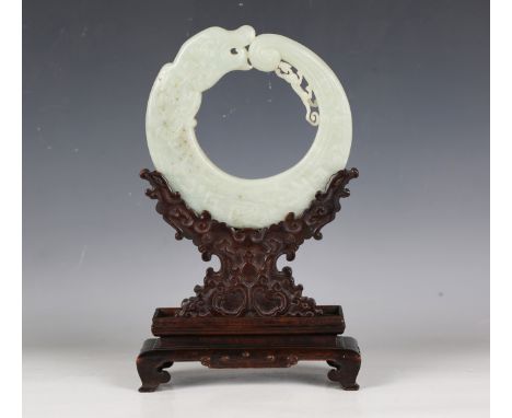 An impressive Chinese archaistic pale celadon jade dragon disc (bi), late Qing dynasty, of flattened circular form, carved in