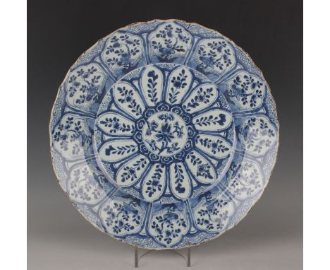 A Chinese blue and white porcelain circular dish, Kangxi period, painted with a central lotus and tendril roundel within radi