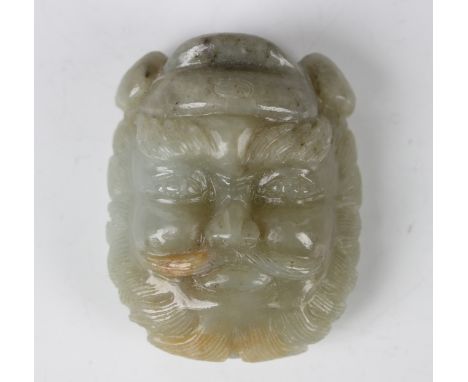 A Chinese pale celadon jade bearded immortal mask buckle/pendant, Qing dynasty, with finely carved facial detail, length 5.5c