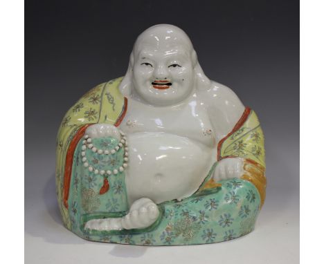 A Chinese porcelain figure of a seated smiling Buddha, early 20th century, modelled wearing an open yellow robe decorated wit