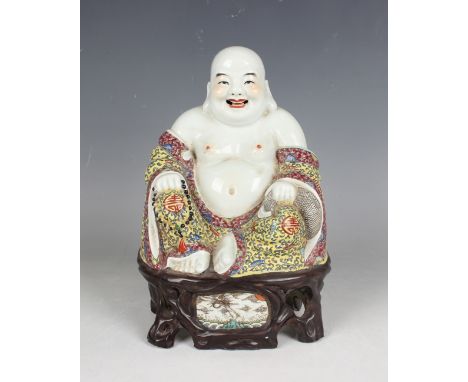 A Chinese porcelain figure of Buddha, early 20th century, modelled seated wearing a colourful robe, on a naturalistic brown g