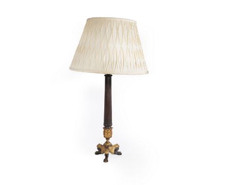 An Empire style table lamp with bronzed metal fluted column and gilt metal triform base, on claw feet and with a pleated shad