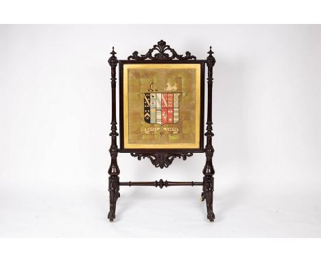 A Victorian armorial fire screen, the needlework panel with the crest of arms of Foljambe, in a carved stained frame on scrol