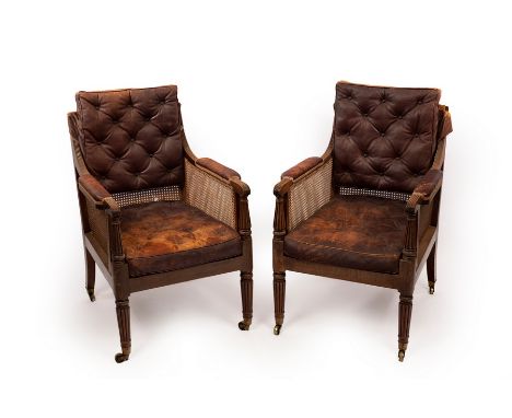 A pair of William IV mahogany library bergère armchairs on front turned tapering reeded legs and brass castors, each fitted l