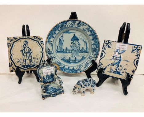 A Delft figure of a rhinoceros, 9cm long, two Delft tiles, a Delft chair and a Delft plate