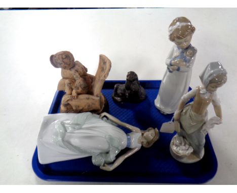 A tray containing three Nao figures together with an Italian Pottery figure, boy with book, and a resin figure, otter family 