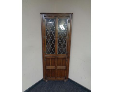 An Ercol elm and beech corner display cabinet with leaded glass doors in an oak finish 