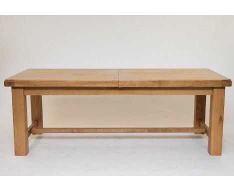 A modern light oak extending dining table, the draw-leaf block top above a plain frieze raised on square section supports uni