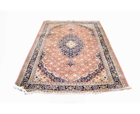 A Tabriz pattern carpet, with dark blue central medallion on a dark pink ground within conforming spandrels and borders, 277c