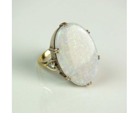 An opal ring, designed as an oval opal plaque claw set in yellow metal to diamond set shoulders, the yellow metal shank stamp