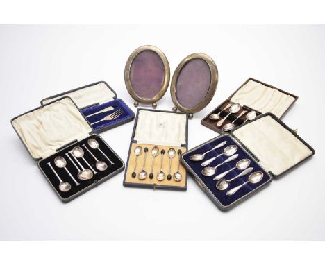 A pair of white metal mounted oval photograph frames, each stamped 'Sterling', 17cm x 13cm, together with a cased set of six 