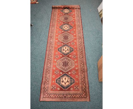 A Persian short runner, 20th century, with geometric guls on a red ground, 222cm x 69cm, together with a rug of similar vinta