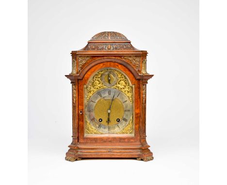 A late 19th century walnut veneered mantel clock, with a domed top carved with foliage, above a 5.5” arched dial with pierced