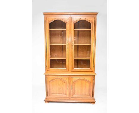 A recent French light oak glazed display cabinet, the ogee cornice above twin glazed doors with moulded arches and external b