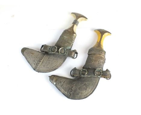 Two Omani khanjar daggers and scabbards19th centurywith characteristic curved blades, white metal-mounted hilts and relief/in