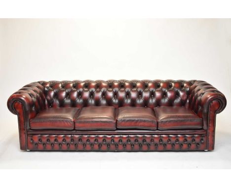 A leather Chesterfield four-seater sofa, late 20th century, of typical button-back scroll-arm form, in a deep red 'antiqued' 