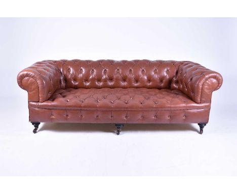 A late Victorian hide covered, buttoned Chesterfield, with close-nailing and turned feet with ceramic castors, one castor par