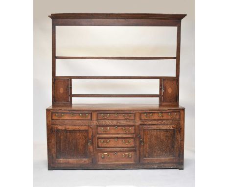 An 18th century Welsh cross-banded oak dresser and rack, the cavetto cornice above three shelves between fluted pilasters and