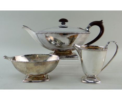 GEORGE V SILVER THREE-PIECE ART DECO TEA SERVICE, Birmingham 1933 by Adie Brothers, rims chased with floral border, Bakelite 