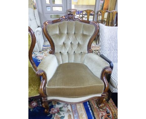 A VICTORIAN STYLE BUTTON BACK ARMCHAIR, with fawn upholstery and carved frame
