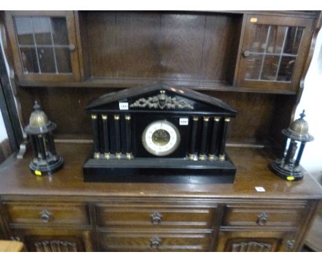 A BLACK MARBLE ARCHITECTURAL MANTEL CLOCK GARNITURE, having circular enamelled dial with Arabic numeral, four pillars either 