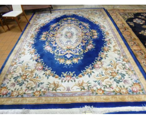 A BLUE GROUND CHINESE FLORAL PATTERNED CARPET, approximate size 370cm x 270cm and a small oatmeal ground rug, approximate siz