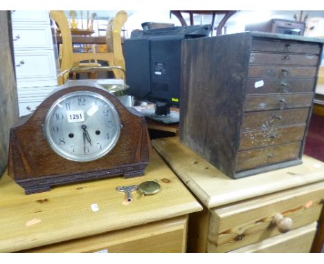 AN OAK CASED MANTEL CLOCK, (key and pendulum) and a small collectors style oak chest of eight graduating drawers (sd) (2)