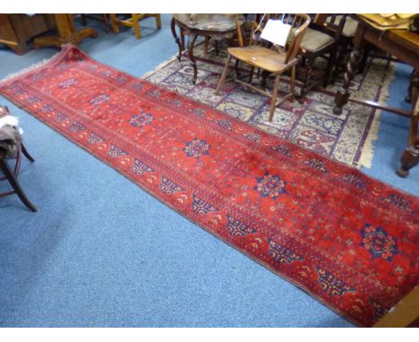 A RED GROUND CARPET RUNNER, approximate size 390cm x 97cm