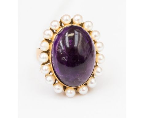 A 14kt gold ring, set with a large oval amethyst cabochon surrounded by seed pearls, approx head size 20mm x 15mm, size I 1/2