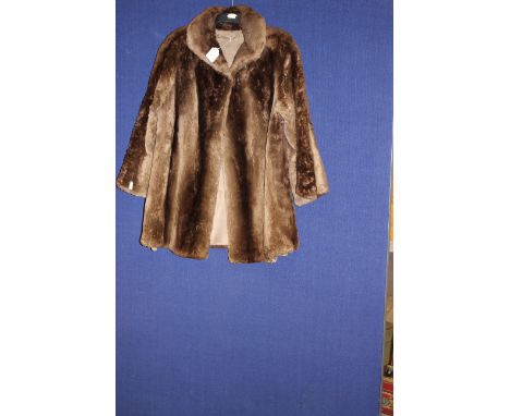 A shaved fur coat in brown, size M-L, hook and eye fastening, round collar and pockets on front hip.