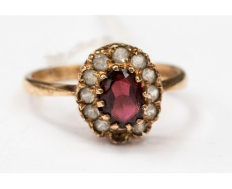 A 9ct gold cluster ring, set with a central oval garnet and white sapphire surround, ( af one white stone missing) set in 9ct